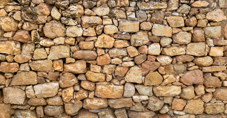 Old rustic dry stone wall background with natural warm earth tones