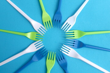 There are many disposable forks on a blue background.