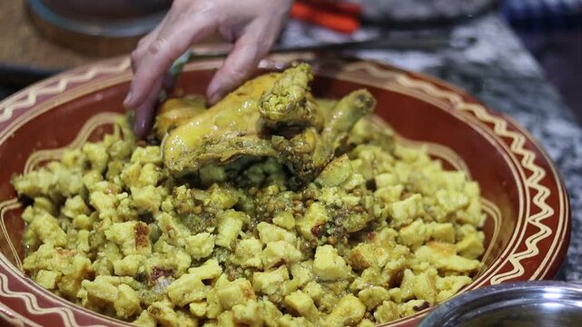 Moroccan Rfissa (Madhoussa) with Slow-Cooked Chicken, Lentils, Semolina Crumbles, and Herbs in Traditional Brown Ceramic Bowl with Garlic Garnish