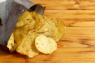 There is a package of potato chips on the wooden table.	