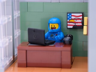 Naklejka premium Tambov, Russian Federation - May 26, 2025 Lego Benny cosmonaut minifigure working behind a laptop on his workplace at the office