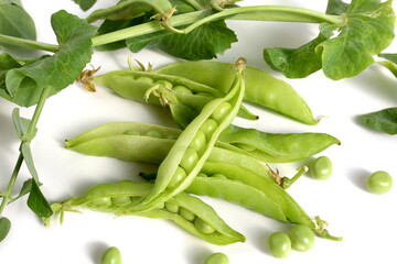 Green pea pods with leaves lie on a white background.	