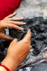 Young woman sculpting clay idol by hand during traditional craft process