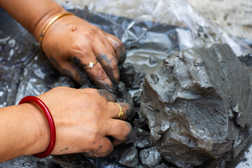 Young woman sculpting clay idol by hand during traditional craft process