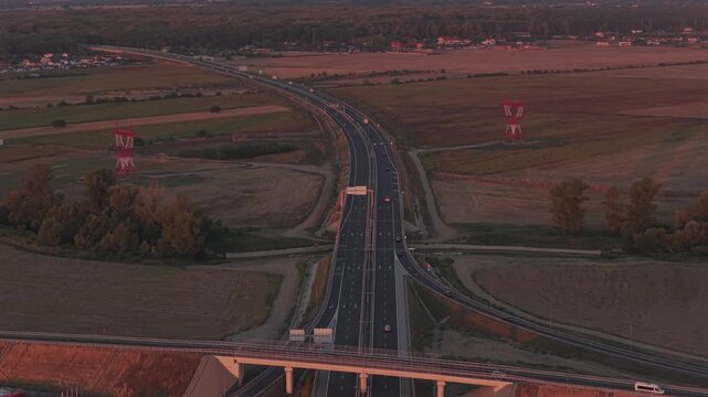 Bucharest A0 highway 4k video. Aerial view of a curved section of the A0 highway near Bucharest during the warm light of sunrise, highlighting the road lines and safety barriers. Roads of Romania.