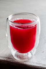 Bright red beverage in a clear glass is ready to be enjoyed on a stylish surface