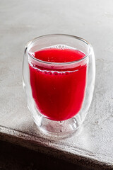 Bright and inviting, a glass of rich red beverage sits on a textured surface, radiating warmth