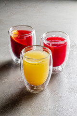 Three vibrant beverages in unique glass cups create a cheerful atmosphere with bold colors