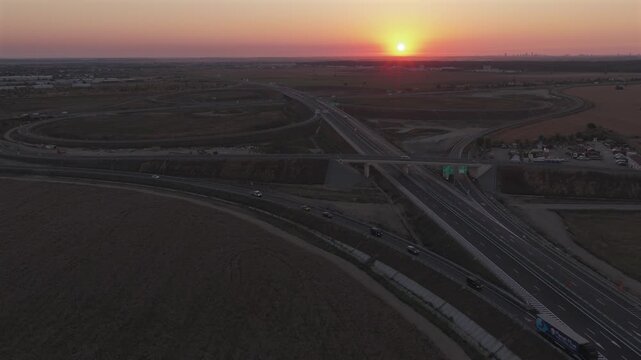 Bucharest A0 highway 4k video. Aerial view of a curved section of the A0 highway near Bucharest during the warm light of sunrise, highlighting the road lines and safety barriers. Roads of Romania.