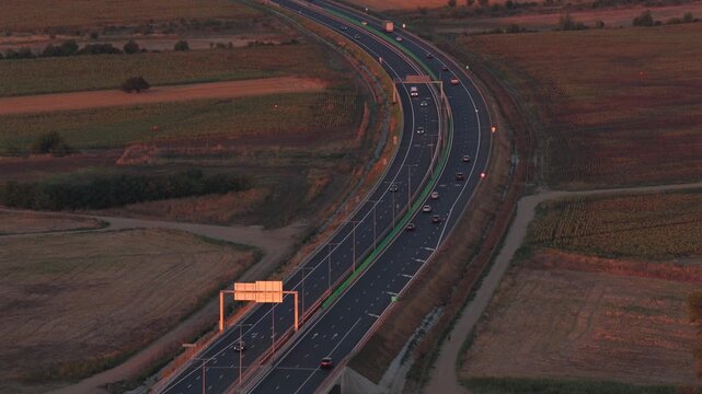 Bucharest A0 highway 4k video. Aerial view of a curved section of the A0 highway near Bucharest during the warm light of sunrise, highlighting the road lines and safety barriers. Roads of Romania.