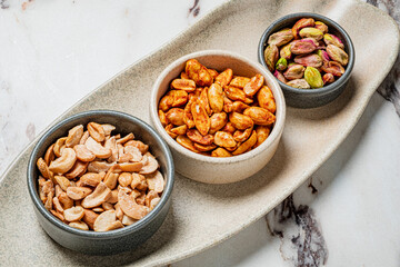 Three bowls filled with assorted nuts bring joy to a vibrant tabletop gathering moment