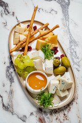 A beautiful cheese platter features assorted cheeses, grapes, olives, and honey for sharing