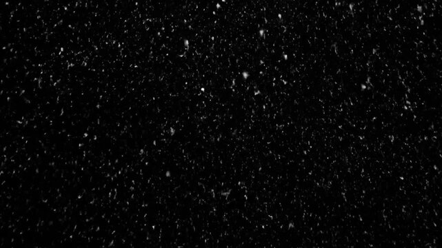 Heavy snowfall continues falling against a dark background in this continuous video clip