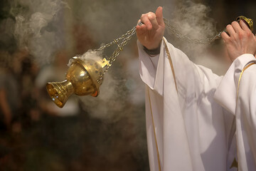 Priest incenses the altar with incense during Holy Mass