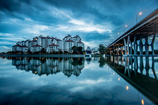 View of serene waters reflecting the Costa Rhu Condominium under a dramatic sky next to the Benjamin Sheares Bridge, Singapore, Singapore.
