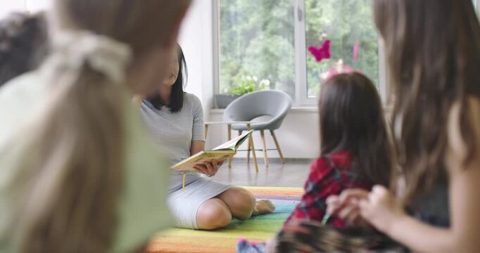 A caring teacher reads to an enthusiastic child with special educational needs. A warm and inclusive classroom setting, highlighting attention and learning support in education.