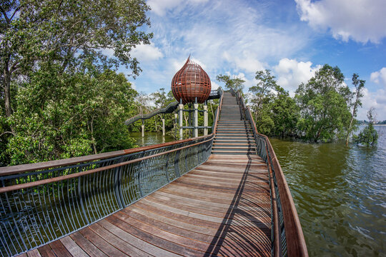 View of boardwalk stretching towards a bulbous structure amidst lush greenery and calm waters, Sungei Buloh Wetland Reserve, Neo Tiew Crescent, Singapore.