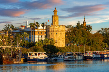 Fototapeta premium Tower of Gold (Torre del Oro) on Guadalquivir river embankment at sunset, Seville, Spain