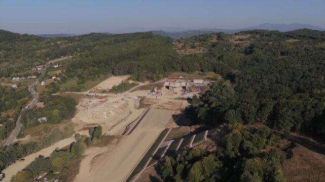 Highway construction in Romania 4k video. Aerial view of the A1 Motorway construction site near Curtea de Arges, showing an unfinished bridge over a valley and forested hills. Bucharest Sibiu road
