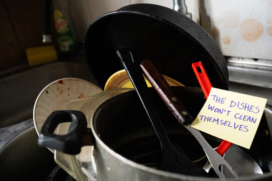 Domestic Humor: Yellow Note with Blue Ink Message on Messy Cookware and Utensils