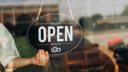 Open sign hanging on glass door of small business shop, welcoming customers. Concept of store...