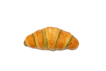 A pistachio croissant is photographed from above, showing its curved shape and green filling lines. The white background keeps focus on texture and color contrast.