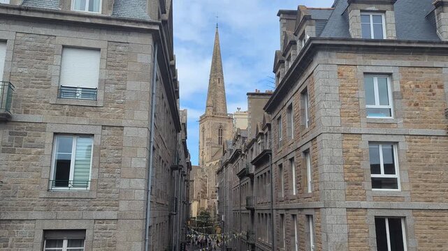 Historic Street View in Rennes France. Narrow alleyways lead to a stunning cathedral spire. A perfect blend of architecture and history captured in this vibrant scene.