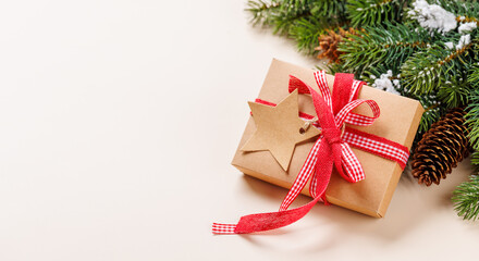 Gift box on snowy fir branches on beige background