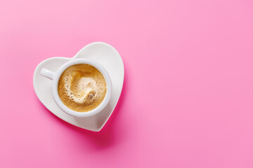 Heart-shaped cappuccino cup on pink background
