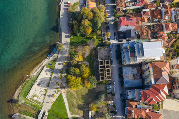 Top-down aerial view of Pogradec, Albania, showing the lakeside promenade of Lake Ohrid, green park areas, and dense urban buildings.
