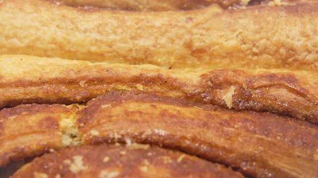 Pastry Layers Extreme Close-Up. An extreme close-up video of laminated pastry layers rotating slowly. The motion emphasizes caramelized ridges, buttery shine, and baked texture.