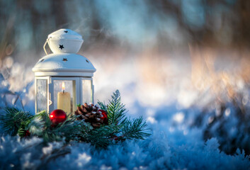Holiday background with spruce wreath and Christmas candlestick standing in New Year's park with shiny crystals of hoarfrost on a frosty morning