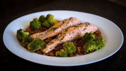 ready to eat - roasted salmon with broccoli and rice served on a white plate