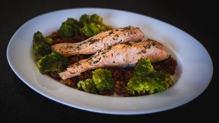 ready to eat - roasted salmon with broccoli and rice served on a white plate