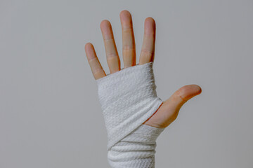 Caucasian adult hand wrapped in white bandage against neutral background
