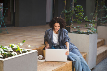  remote workers. Working from Anywhere.  middle aged woman    is working on a laptopon a bench on the street in a cafe. startup
