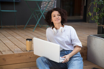  remote workers. Working from Anywhere.  middle aged woman    is working on a laptopon a bench on the street in a cafe. startup
