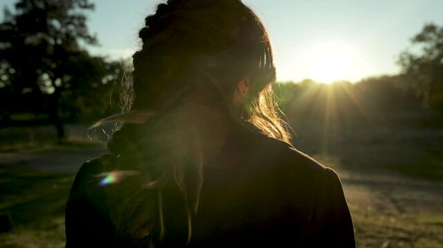 Mujer pasea por el campo al anochecer y se gira para mirar a c&aacute;mara 