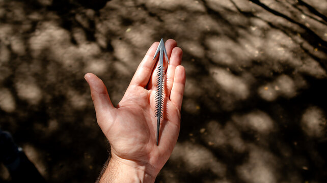 A hand holding a unique arrowhead