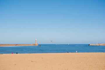 Sunderland UK: 16th July 2025: sandy Roker Beach in Sunderland. The sun shines brightly and boats can be seen on the water. A lighthouse stands in the distance.