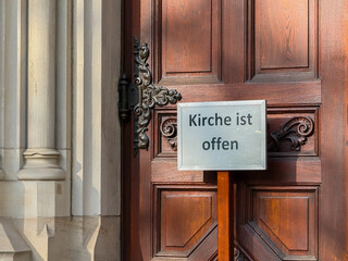 Church is open german text near wooden door