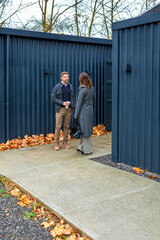 Real estate agent discussing with client standing outside of a modern modular house built from repurposed shipping containers. Contemporary sustainable and eco friendly architecture concept.