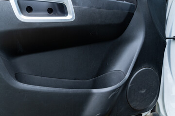 Car door panel with speaker grille and screw holes on textured surface