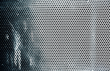 Superficie met&aacute;lica perforada azul verdosa con patr&oacute;n circular.Rejilla o frontal de altavoz