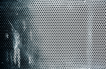 Superficie metálica perforada azul verdosa con patrón circular.Rejilla o frontal de altavoz