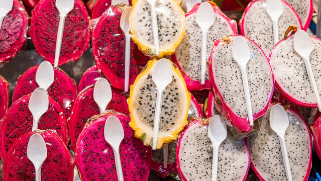 Dragon fruit halves with white plastic spoons