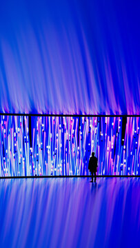 Man looks at digital screen with vibrant patterns in dark room