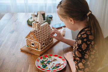 Girl decorating gingerbread house for Christmas celebration