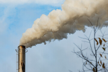 Smoke rising from an industrial chimney under blue sky
