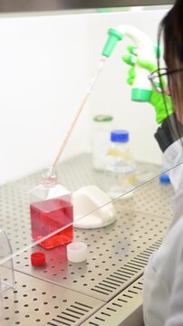 Female scientist pipetting liquid in a laminar flow hood.Vertical video